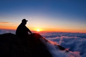 山頂で朝日を見る男性