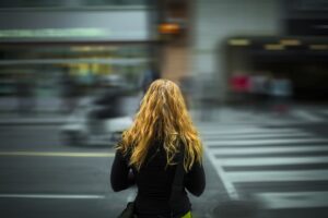 横断歩道で立ち止まる金髪の女性